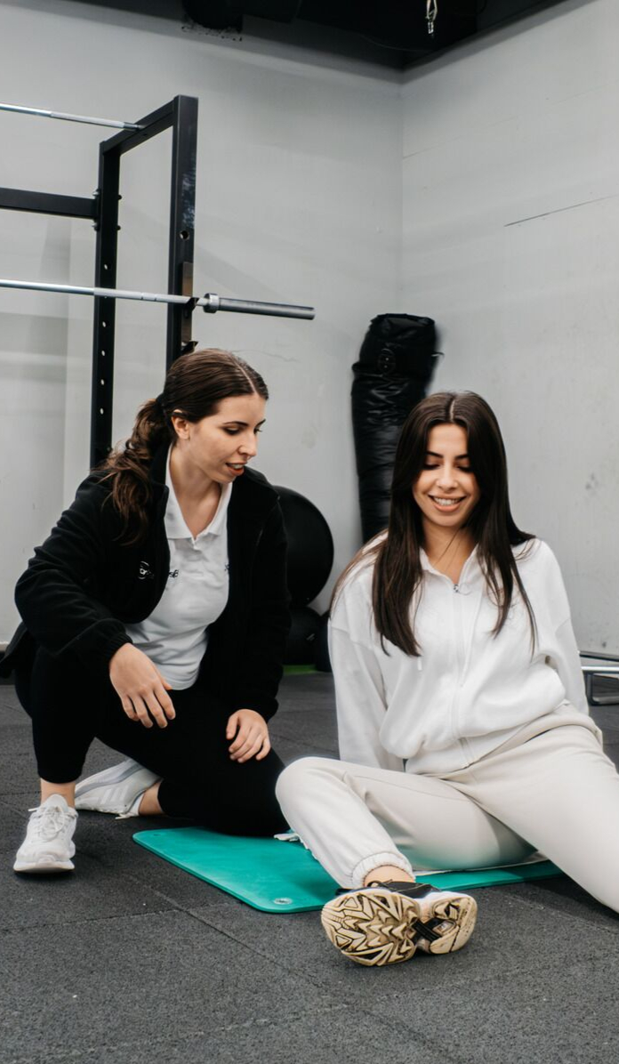 Imagem de uma profissional de fisioterapia a ajudar uma paciente num exercício de mobilidade.